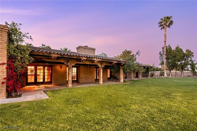 back of property with french doors, a yard, a chimney, and a patio area