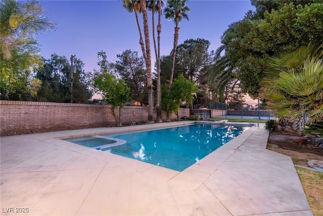 view of swimming pool with a patio area, a pool with connected hot tub, and a fenced backyard