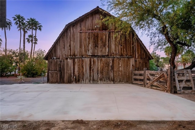outdoor structure at dusk featuring an outdoor structure, fence, and a barn