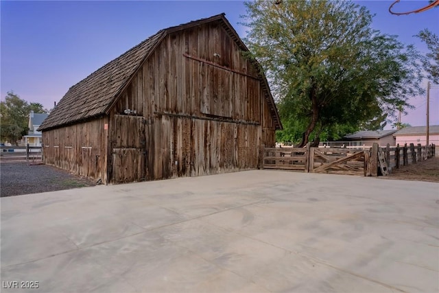 outdoor structure at dusk with an outdoor structure, fence, and a barn