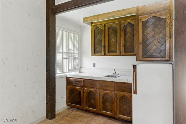 bar with freestanding refrigerator, baseboards, and a sink