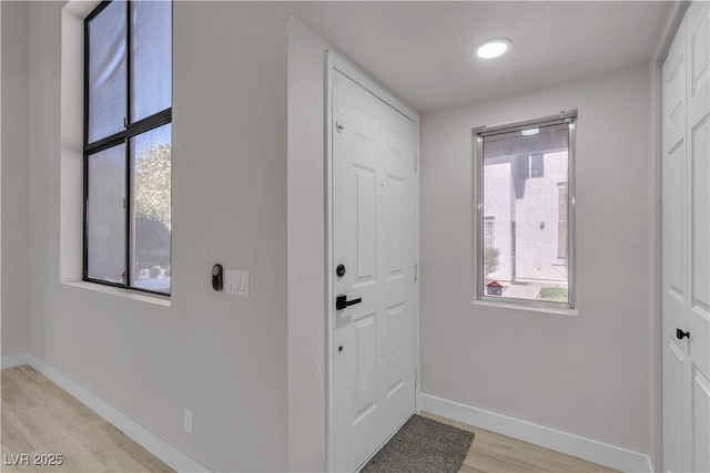 doorway to outside with light wood-style flooring and baseboards