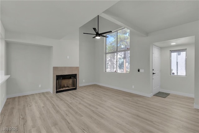 unfurnished living room with a fireplace, a wealth of natural light, baseboards, and light wood-style floors