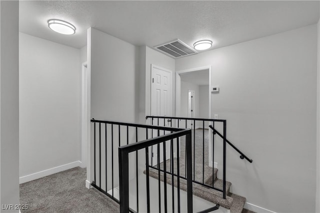 interior space with carpet floors, a textured ceiling, baseboards, and visible vents