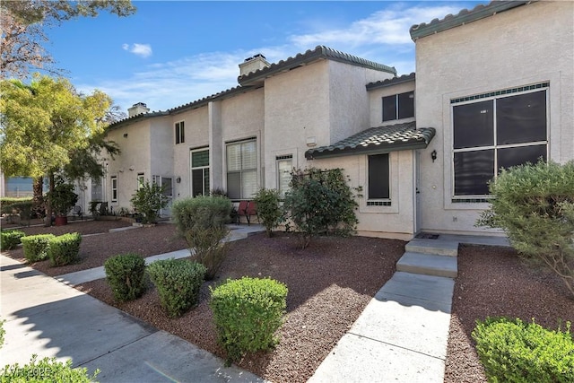 view of front of property with a chimney, stucco siding, and a tile roof
