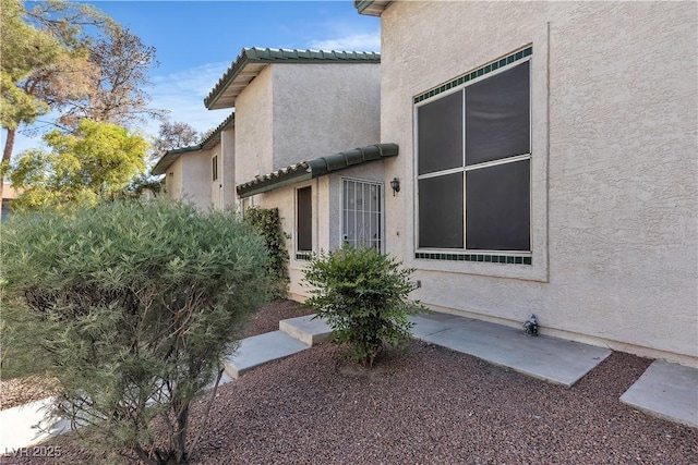 view of exterior entry featuring a tile roof and stucco siding