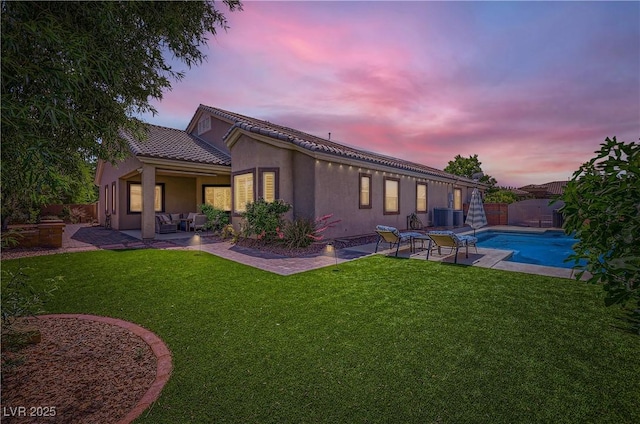 back of house at dusk with a patio, an outdoor living space, cooling unit, and stucco siding
