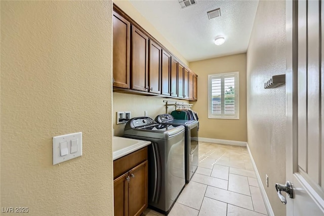 clothes washing area with independent washer and dryer, cabinet space, baseboards, a textured ceiling, and a textured wall