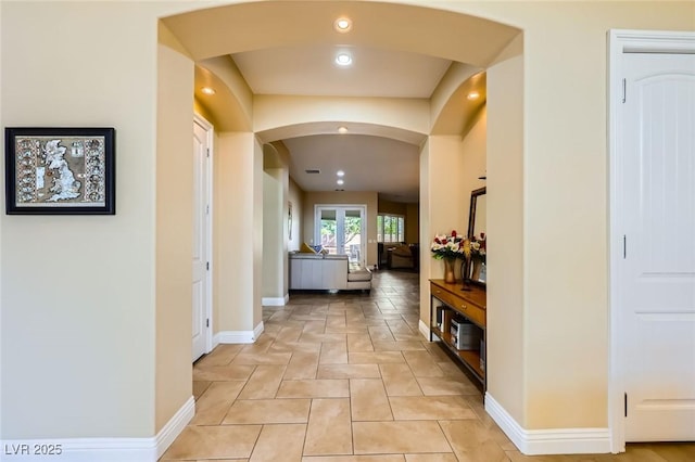 corridor featuring arched walkways, baseboards, and recessed lighting