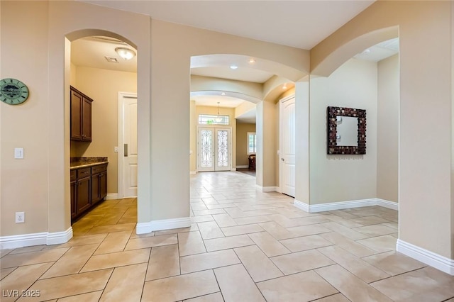 hall with arched walkways, baseboards, light tile patterned flooring, and recessed lighting