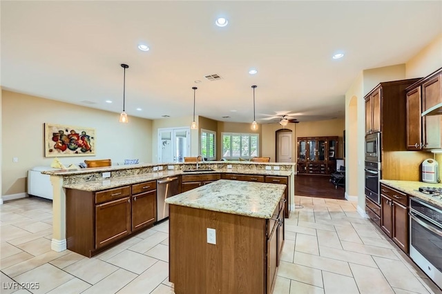 kitchen with stainless steel appliances, a large island with sink, a sink, recessed lighting, and hanging light fixtures
