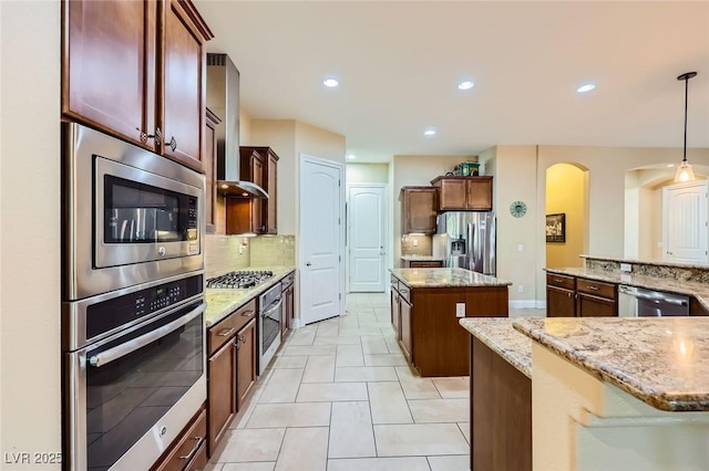 kitchen featuring stainless steel appliances, a kitchen island, backsplash, arched walkways, and hanging light fixtures