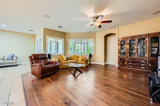 living room featuring ceiling fan, arched walkways, baseboards, and wood finished floors