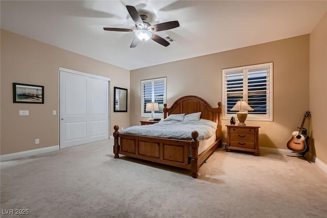 bedroom with light colored carpet, a closet, baseboards, and a ceiling fan