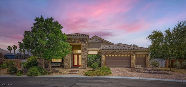 7418 Lawrence Powers Ct, Las Vegas, NV 89129 - view of front facade with stone siding, an attached garage, driveway, a tile roof, and stucco siding