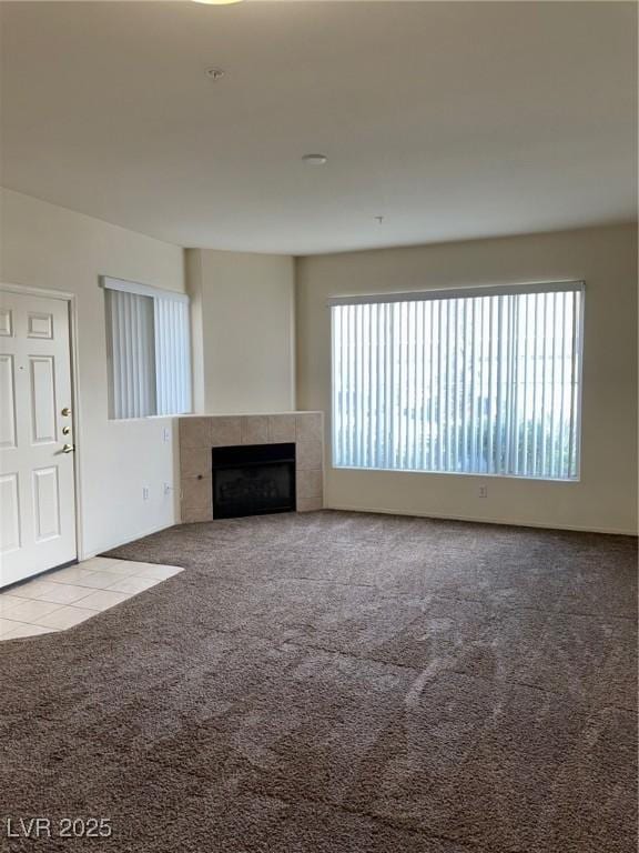 unfurnished living room with a tile fireplace and carpet