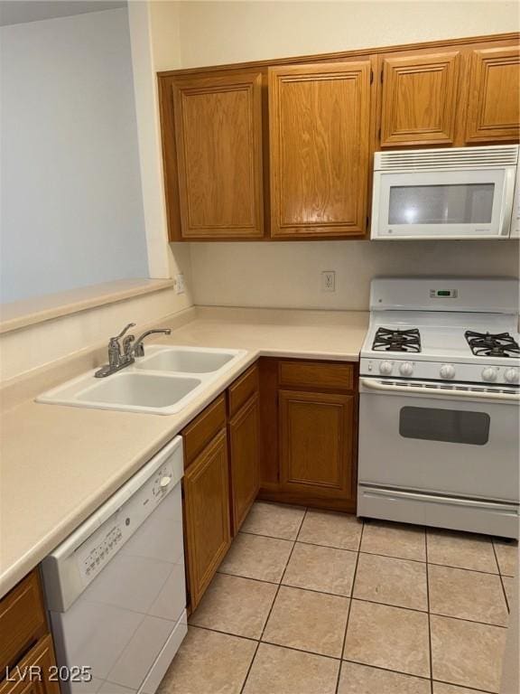 kitchen with brown cabinets, white appliances, light countertops, and a sink