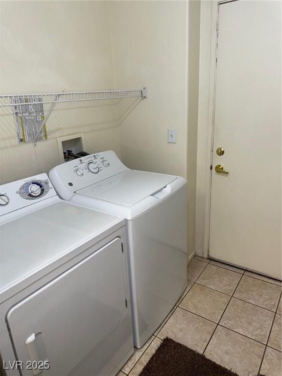 clothes washing area featuring laundry area, washer and clothes dryer, and light tile patterned flooring