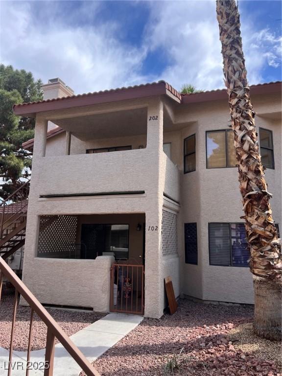 809 Rock Springs Dr Unit 202, Las Vegas, NV 89128 - view of front of home featuring stairs, stucco siding, a balcony, a gate, and a chimney