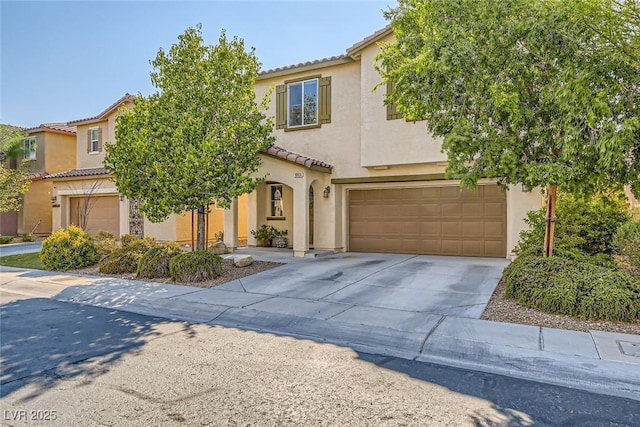 mediterranean / spanish house with driveway, stucco siding, a tiled roof, and an attached garage