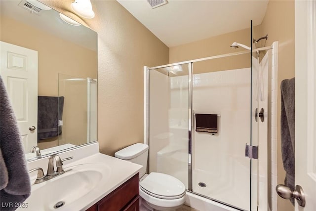 bathroom featuring vanity, toilet, visible vents, and a shower stall