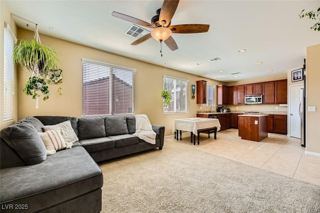 living room with light tile patterned flooring, visible vents, baseboards, and a ceiling fan