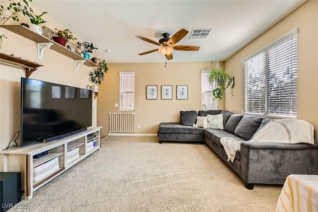 carpeted living area with a ceiling fan, radiator, baseboards, and visible vents