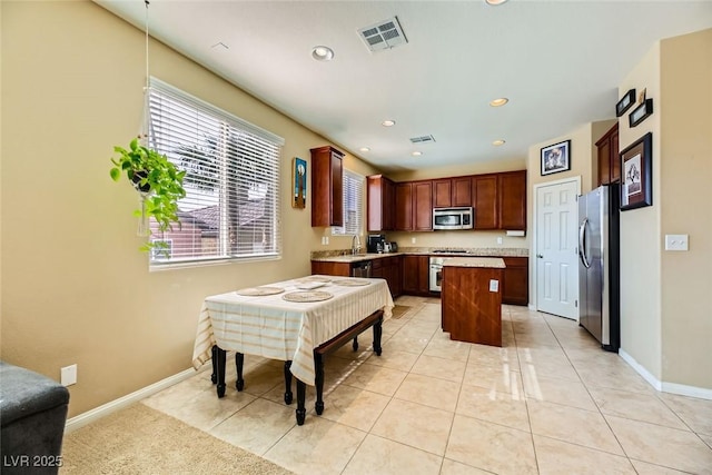 kitchen with baseboards, stainless steel appliances, visible vents, and a center island