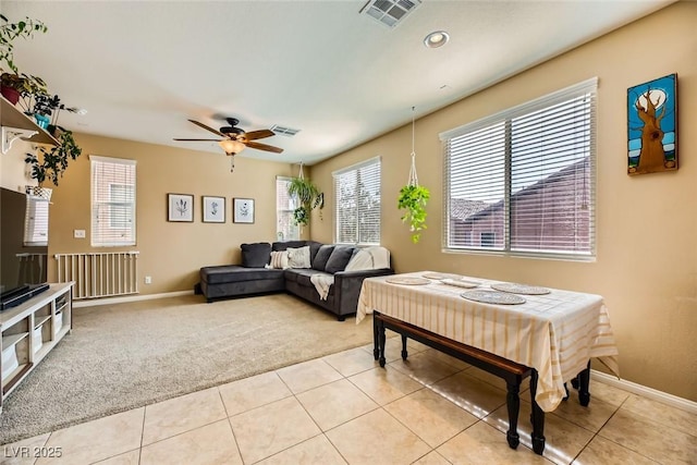 carpeted living room with tile patterned flooring, baseboards, ceiling fan, and visible vents