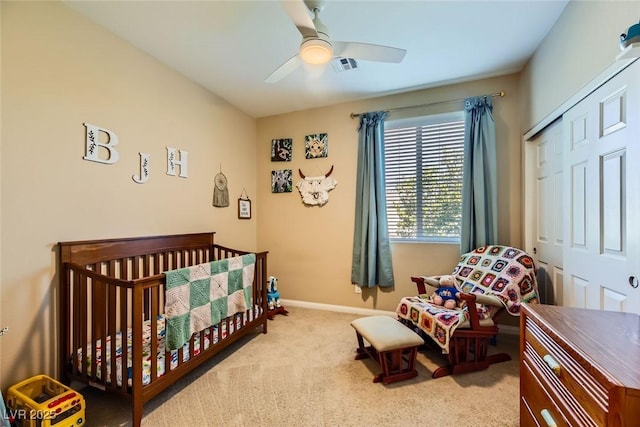 carpeted bedroom with a ceiling fan, a closet, a nursery area, visible vents, and baseboards
