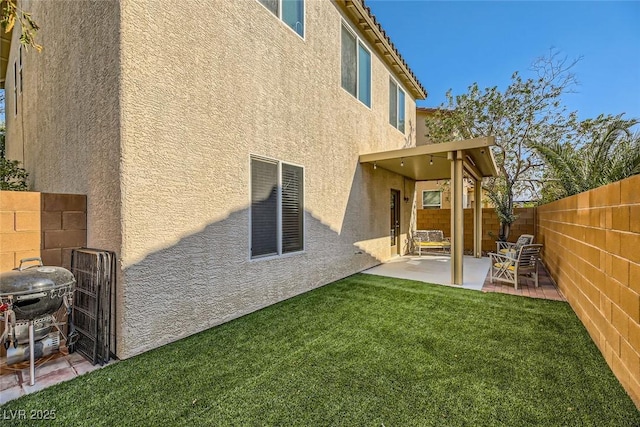 rear view of property featuring a yard, stucco siding, a fenced backyard, and a patio area