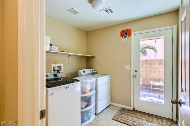 clothes washing area featuring washing machine and dryer, light tile patterned floors, visible vents, and laundry area