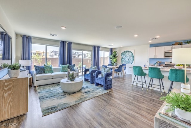 living room with visible vents, wood finished floors, baseboards, and recessed lighting