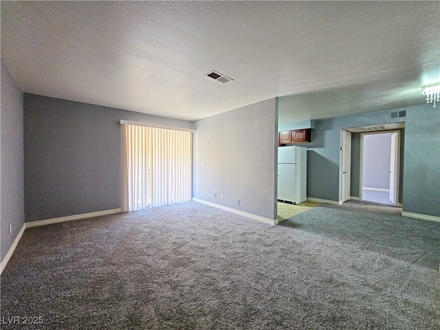 spare room featuring light colored carpet, a textured ceiling, baseboards, and visible vents