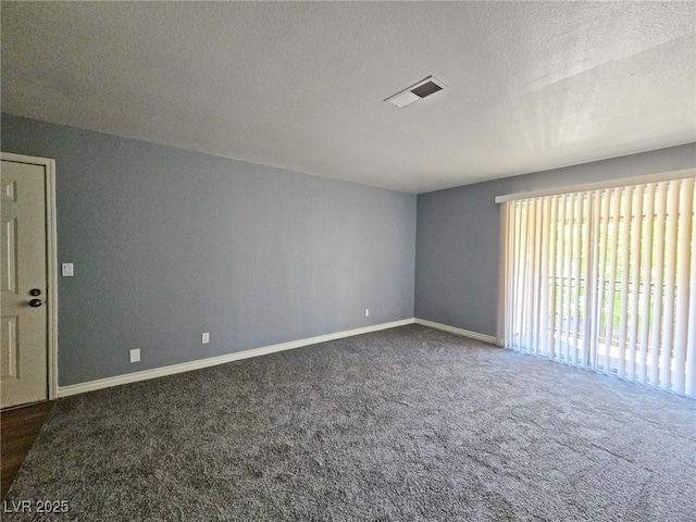 unfurnished room featuring dark colored carpet, a textured ceiling, baseboards, and visible vents
