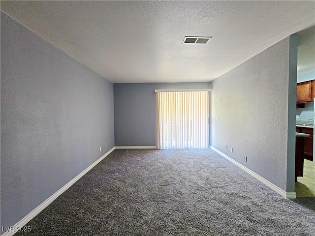 carpeted spare room with baseboards, visible vents, a textured ceiling, and a textured wall
