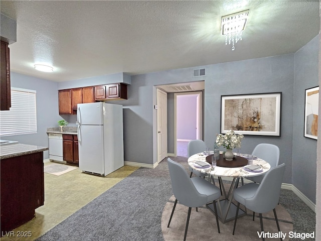 dining room with baseboards, visible vents, and a textured ceiling