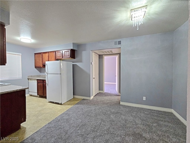 kitchen with a textured ceiling, baseboards, white appliances, visible vents, and light countertops