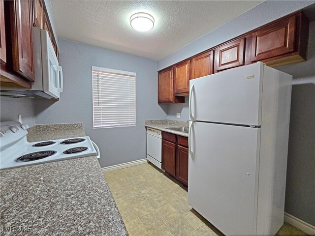kitchen featuring baseboards, white appliances, a sink, and a textured ceiling