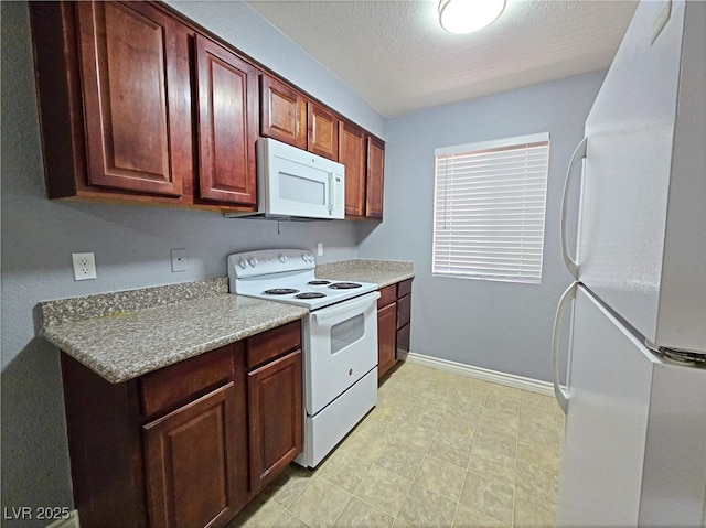 kitchen featuring light countertops, baseboards, and white appliances