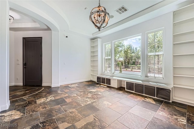 mudroom with a tray ceiling, a notable chandelier, built in features, baseboards, and arched walkways