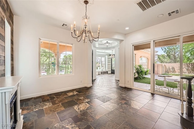 unfurnished dining area featuring visible vents, baseboards, and a notable chandelier