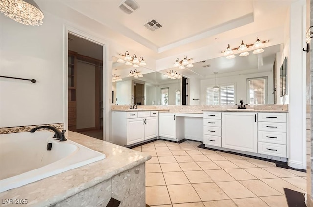 full bath with a sink, a raised ceiling, a garden tub, and visible vents