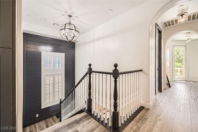 interior space with a notable chandelier, arched walkways, baseboards, and wood finished floors