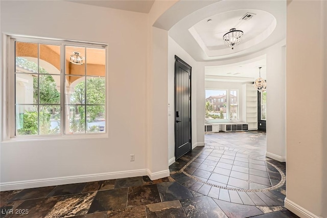 foyer featuring an inviting chandelier, stone tile flooring, visible vents, baseboards, and arched walkways