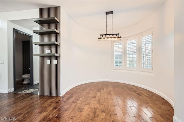 unfurnished dining area featuring baseboards and wood-type flooring