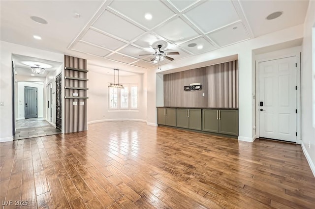 unfurnished living room with baseboards, ceiling fan, coffered ceiling, and hardwood / wood-style flooring