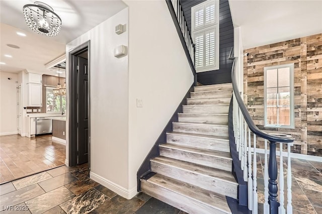 staircase featuring recessed lighting, an inviting chandelier, baseboards, and stone tile floors