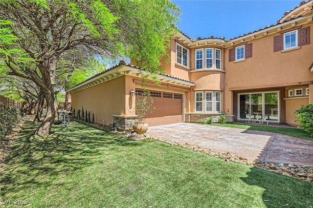 back of property featuring a yard, a tiled roof, stucco siding, concrete driveway, and stone siding
