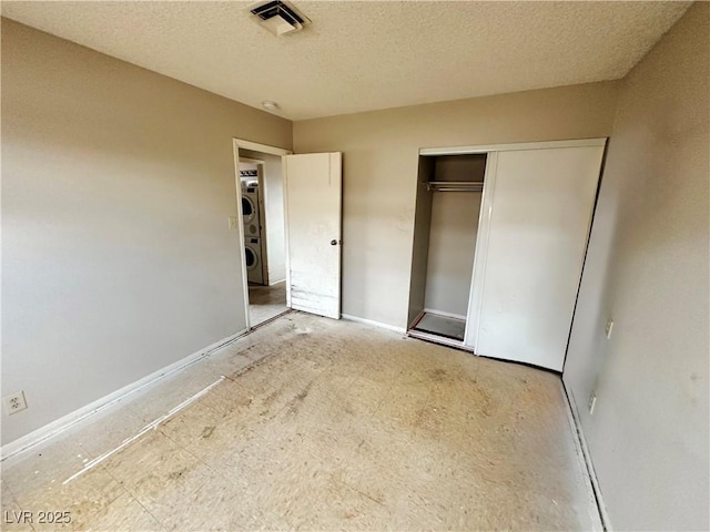 1004 Stone River Dr, North Las Vegas, NV 89030 - unfurnished bedroom featuring stacked washer / dryer, a textured ceiling, a closet, and baseboards